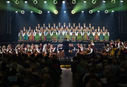 Na scenie Artyści Chóru w kostiumach łowickich, niżej Artyści Orkiestry w kostiumach wilanowskich wraz z Dyrektorem