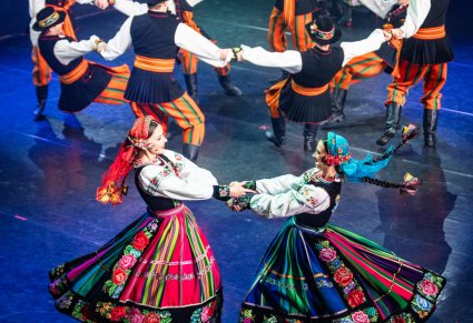 Artyści w kostiumach łowickich podczas wykonywania choreografii tanecznej na scenie