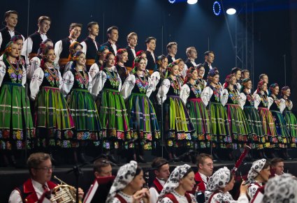 Na scenie Artyści Chóru w kostiumach łowickich, niżej część Artystów Orkiestry w kostiumach wilanowskich