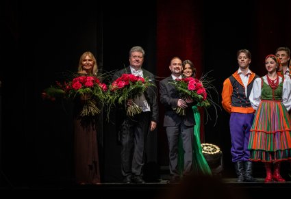 Na scenie z kwiatami Dyrektor zespołu, Kierowniczka baletu, Kierownik chóru oraz konferansjerka, obok część Artystów w kostiumach sannickich