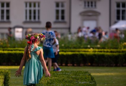 Mała dziewczynka z wiankiem na głowie zmierza w stronę Pałacu w Karolinie