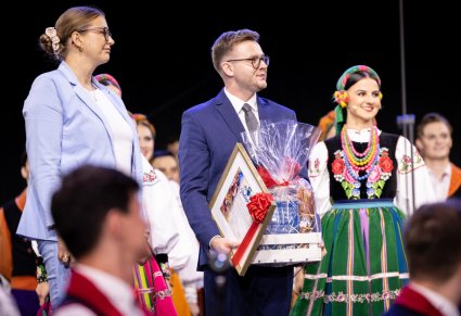 Dyrygent zespołu odbierający podziekowania i upominki od gospodarzy po koncercie