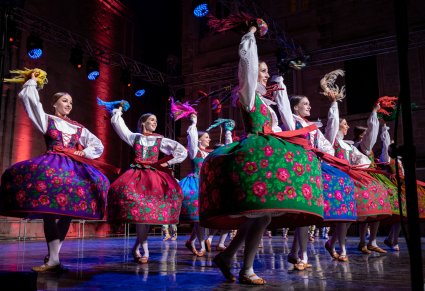 Artystki na scenie w kostiumach podhalańskich kręcące się i machające chustami