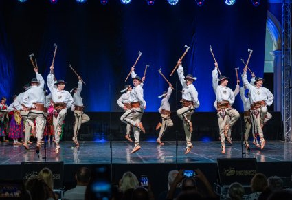 Artyści w trakcie wykonywania choreografii na scenie w kostiumach podhalańskich