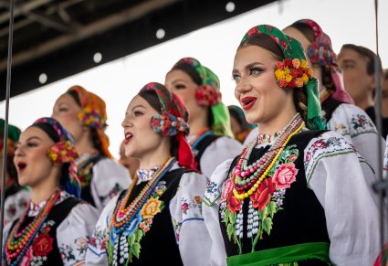 Zbliżenie na śpiewające Artystki Chóru w kostiumach łowickich na scenie
