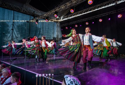 Artyści na scenie w parach w trakcie wykonywania choreografii tanecznej w kostiumach opoczyńskich