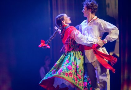 Zbliżenie na parę Artystów w kostiumach ludowych którzy wykonują choreografię taneczną