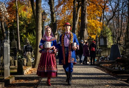 Para Artystów w kostiumach podegrodzkich trzymająca w rękach puszki na datki, które wspierają odbudowę Starych Powązek
