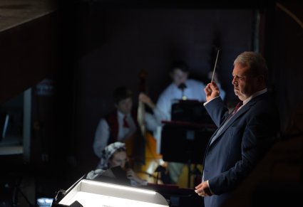 Zbliżenie na Dyrektora zespołu w trakcie dyrygowania Orkiestrze