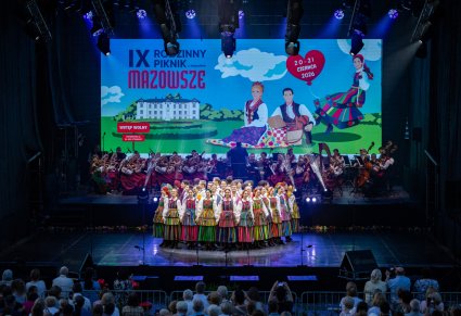 Na scenie Artyści w kostiumach ludowych podczas wykonywania pierwszego taneczno-wokalnego utworu, w tle widoczna Orkiestra w kostiumach wilanowskich wraz z Dyrygentem