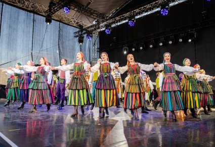 Na scenie grupa Artystów w kostiumach opoczyńskich podczas śpiewu i wykonywania choreografii
