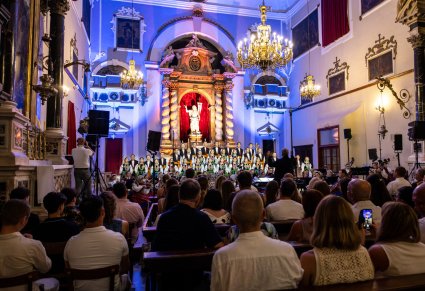 Na pierwszym planie publiczność na drugim Artyści z Chóru w kostiumach łowickich. Koncert odbywa się w przestrzeni kościelnej