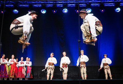 Artyści w trakcie wykonywania choreografii na scenie w kostiumach podhalańskich
