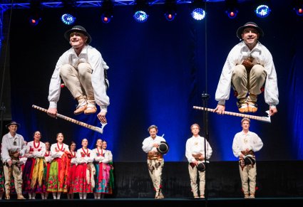 Tancerze podczas wykonywania choreografii tanecznej na scenie w kostiumach podhalańskich