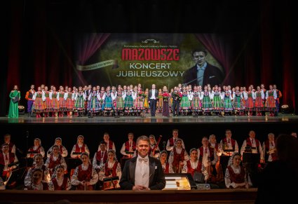 Na pierwszym planie Dyrygent, następnie orkiestra w kostiumach wilanowskich. Na scenie Artyści w kostiumach ludowych wraz z Dyrektorem, Kierowniczką baletu, Kierownikiem chóru i konferansjerka