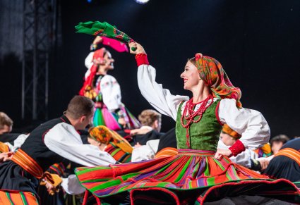 Grupa tancerzy na scenie w kostiumach sannickich i kostiumach łowickich