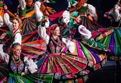 Zbliżenie na Artystki w kostiumach ludowych podczas wykonywania choreografii tanecznej na scenie