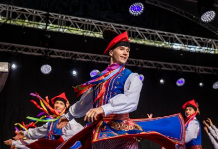 Artyści w kostiumach krakowskich na scenie w trakcie wykonywania choreografii tanecznej