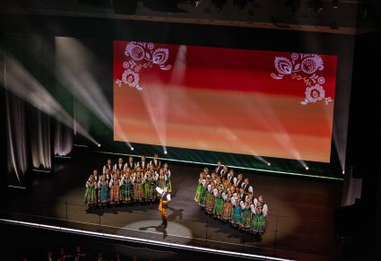 Na środku sceny Solista po jego bokach Artyści Chóru w kostiumach łowickich