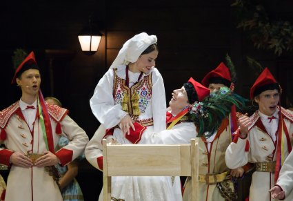 Zbliżenie na Parę Młodą w kostiumach krakowskich przy kołysce, w tle widoczna część Artystów również w kostiumach krakowskich