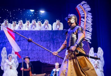 Zbliżenie na postać Husarza Skrzydlatego, w tle Stajenka z Aniołami na dachu