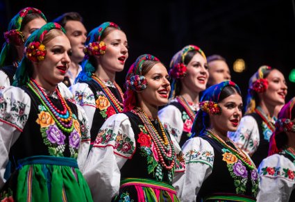 Zbliżenie na chórzystów na scenie w kostiumach łowickich