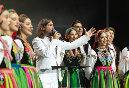 Zbliżenie na solistę zespołu Pectus, który śpiewa wraz z Artystami Chóru, którzy mają na sobie kostiumy łowickie