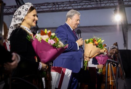Zbliżenie na przemawiajacego Dyrektora zespołu trzymającego bukiet kwiatów oraz koncertmistrzynię w kostiumie wilanowskim także z bukietem kwiatów
