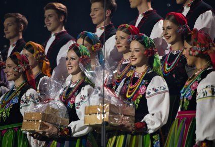 Zbliżenie na Artystów Chóru w kostiumach łowickich, dwie Artystki trzymają w ręku drobne prezenty od Organizatorów