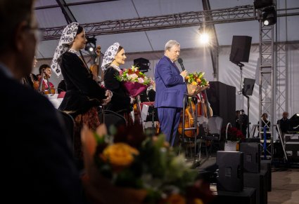 Dyrektor zespołu i koncertmistrzyni w kostiumie wilanowskim z bukietami kwiatów wręczonymi po koncercie, widoczna także część orkiestry