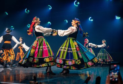 Zbliżenie na dwie Artystki w kostiumach łowickich w trakcie wykonywania choreografii tanecznej