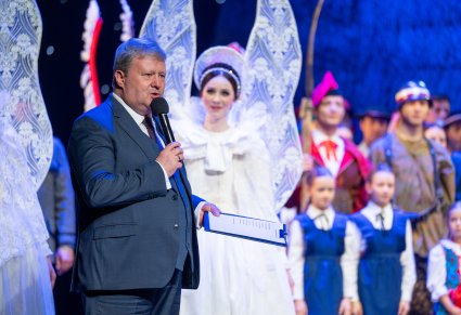 Dyrektor zespołu "Mazowsze" wypowiadający się na scenie do mikrofonu, w tle część Artystów grająca w widowisku "Betlejem Polskie"