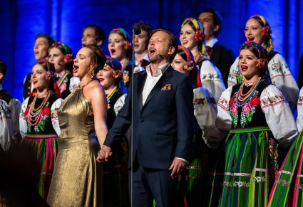 Zbliżenie na Parę solistów a za nimi chór w kostiumach łowickich