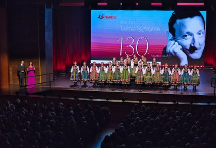 Na scenie Artyści Chóru w kostiumach łowickich oraz prowadzący i prowadząca koncert