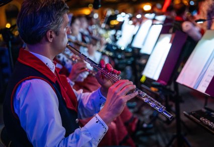 Zbliżenie na członka orkiestry z instrumentem i nutami