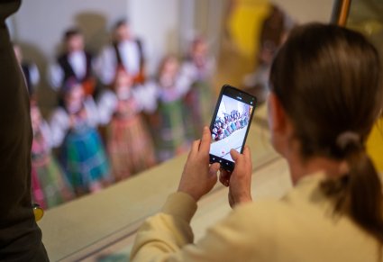 Na pierwszym planie Kobieta nagrywający koncert na telefon