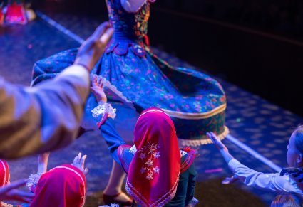 Widok na kręcącą się wkoło Artystkę w kostiumie ludowym i małe dziewczynki