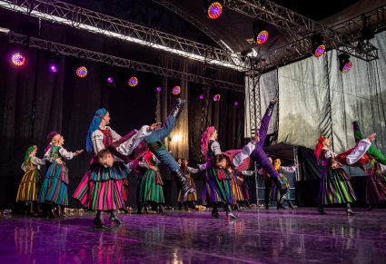 Artyści na scenie w kostiumach opoczyńskich w trakcie wykonywania spektakularnej choreografii tanecznej