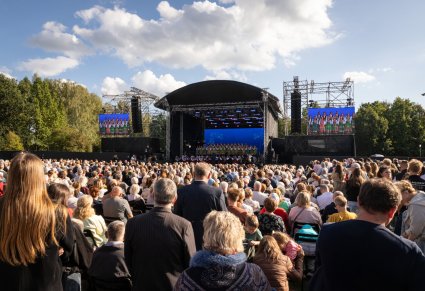 Widok na Publiczność zebraną podczas koncertu zespołu "Mazowsze", na scenie Chór w kostiumach łowickich wraz z orkiestrą w kostiumach wilanowskich