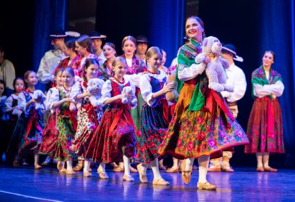 Na scenie grupa przedszkolaków w kostiumach podhalańskich, trzymająca w rękach pluszowe misie, idące za Artystką