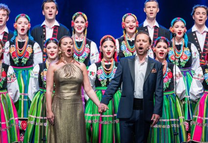 Artyści w trakcie śpiewu na scenie w kostiumach łowickich