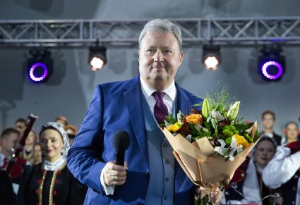 Zbliżenie na Dyrektora zespołu trzymającego bukiet kwiatów