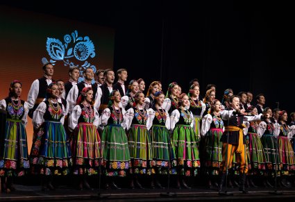 Na pierwszym planie Solista wykonujący utwór "Furman", za nim Artyści Chóru w kostiumach łowickich