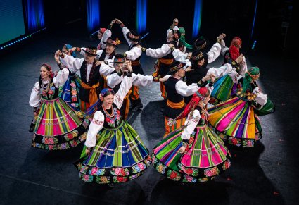 Artyści w kostiumach łowickich w trakcie wykonywania choreografii tanecznej
