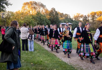 Artyści w kostiumach łowickich, wychodzący z koncertu, obserwowani przez publiczność