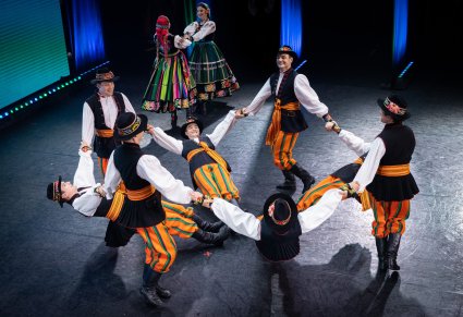Grupa Artystów w kostiumach łowickich w trakcie wykonywania choreografii tanecznej