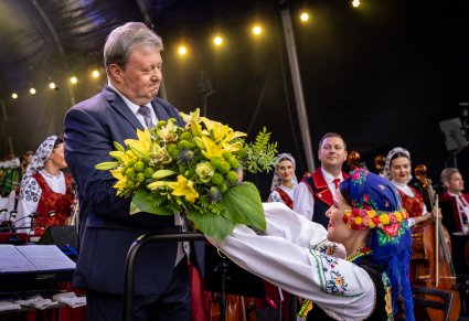 Artystka z Zespołu wręcza Dyrektorowi Jackowi Bonieckiego kwiaty na scenie