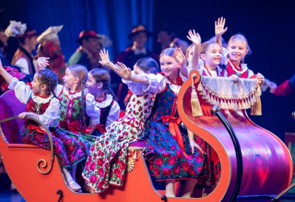 Dziewczynki grające w spektaklu siedzące w czerwonych saniach