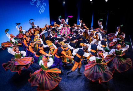 Na scenie Artyści w kostiumach ludowych podczas wykonywania charakterystycznej figury choreografii tanecznej