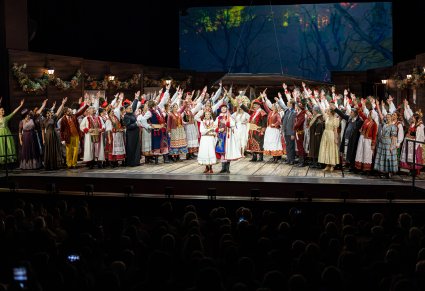 Na środku sceny Para młoda w krakowskich kostiumach , po bokach sceny pozostali Artyści